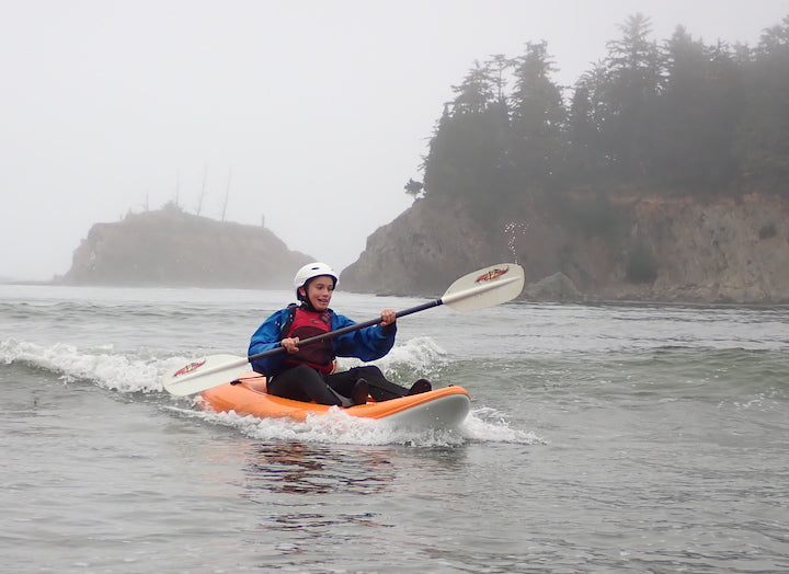 kid learning how to kayak surf, using Aqua Bound paddle