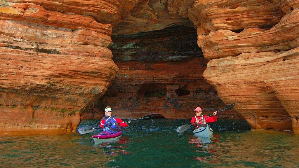 Two kayakers paddling through a sea cave in Apostle Islands National Lakeshore