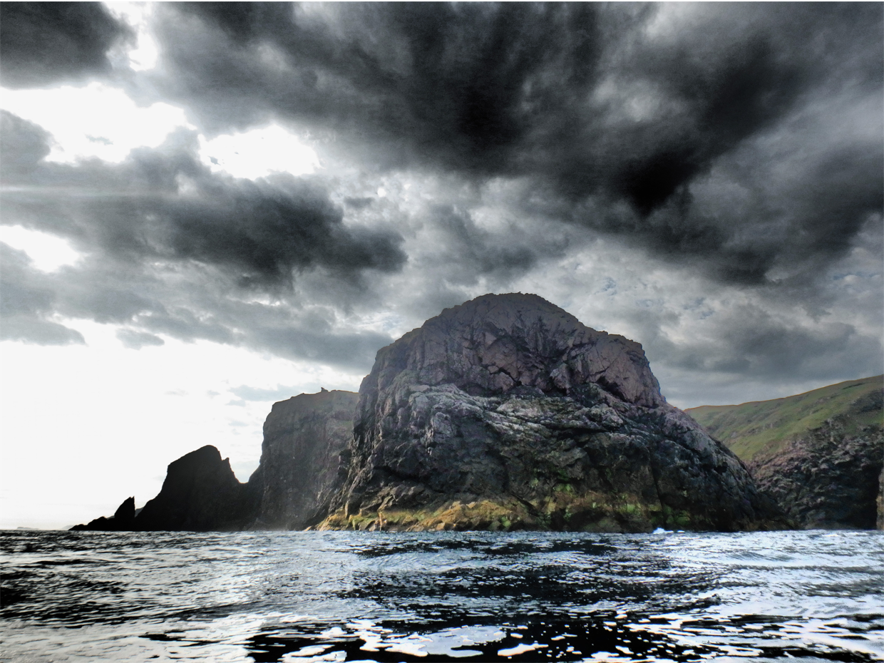 Moody, cloudy skies behind a beautiful rock formation in the costal seas