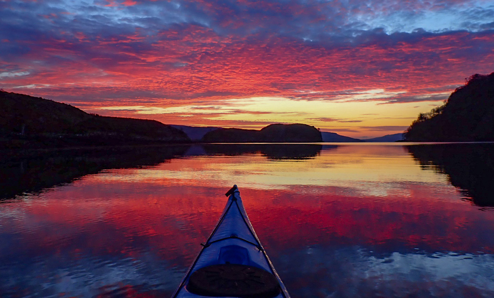 Red, purple, deep blue sunset sky with bow of kayak 