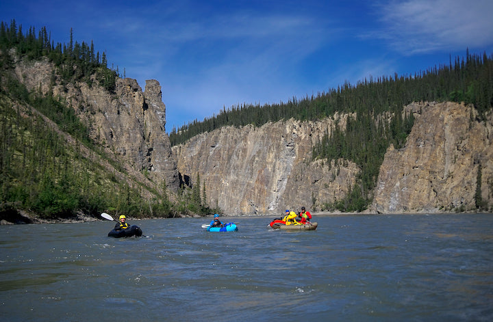 packrafters on the Nahanni River surrounded by high cliffs
