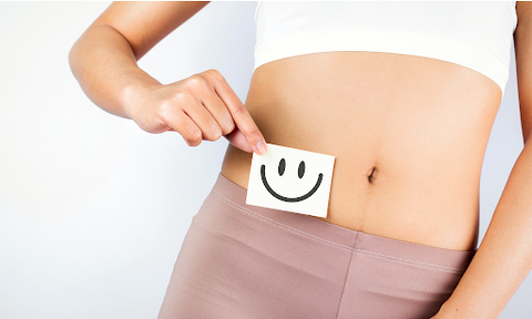 Frau hält sich lachenden Smiley an den Bauch