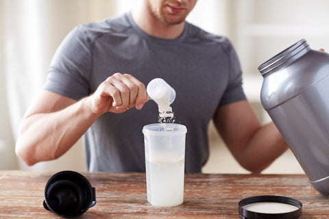 Mann füllt Proteinpulver in einen Shaker