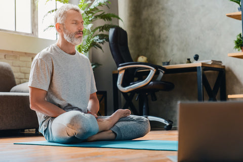 Ein Mann meditiert auf einer Yogamatte