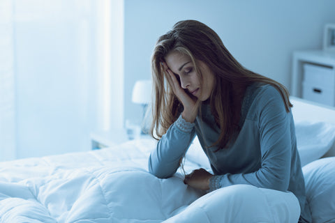 Frau sitzt müde im Bett