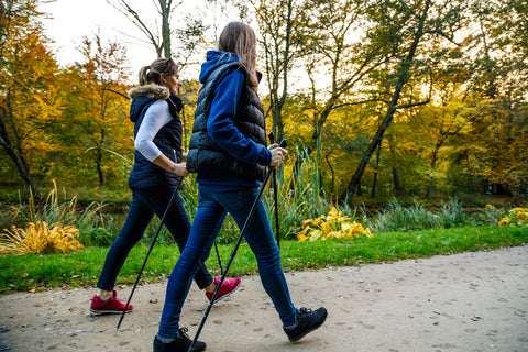 Zwei Personen machen draußen Nordic Walking