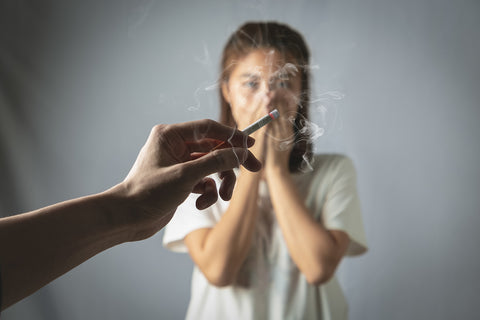 Frau hält sich die Nase zu wegen Zigarettenrauch