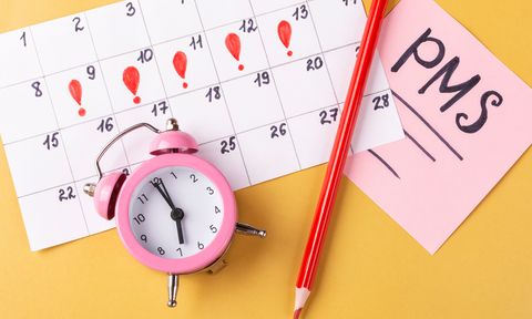 Kalender, Wecker, Bleistift und Zettel mit Aufschrift PMS