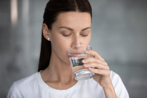 Frau trinkt Wasser aus einem Glas