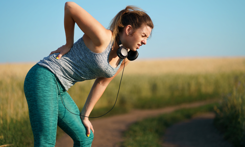 Frau hat beim Joggen Rückenschmerzen