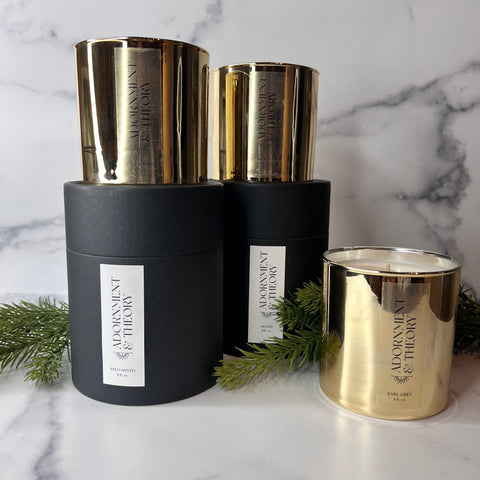 Three golden candles - two on top of black cylindrical boxes and the third on the marble base.