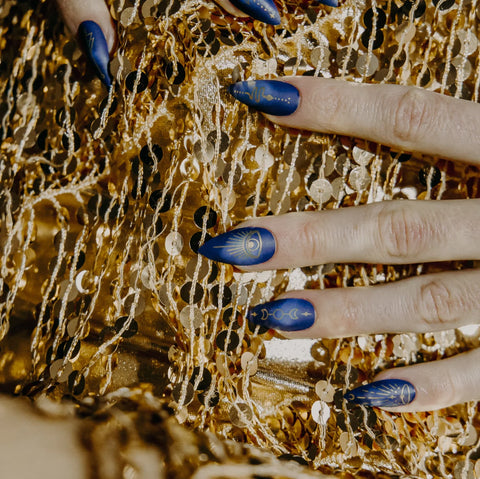 Hands on a glitter background. The nails are tipped with beautiful blue press-ons with a celestial design