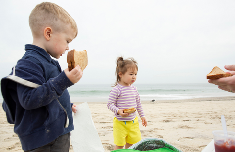 children eating sandwiches on the beach