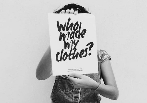 Women holding sign saying who made my clothes 