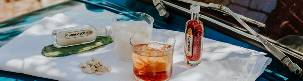 Image of two variations of Adriatico Amaretto on the bonnet of a vintage car