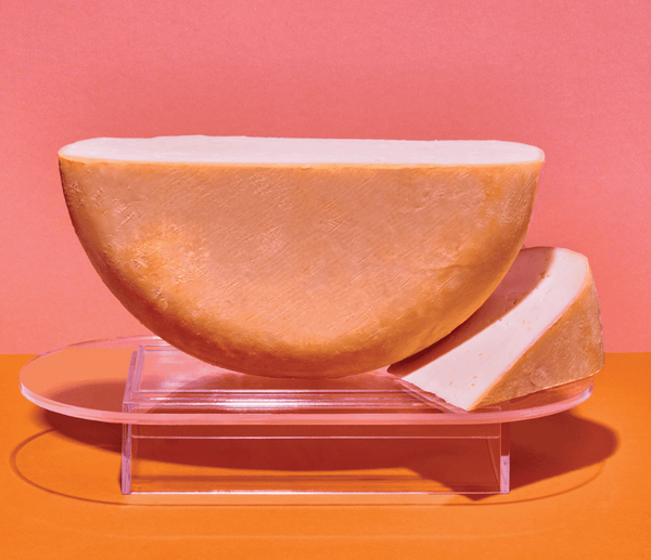 Half wheel of cheese with wedge on oval platter