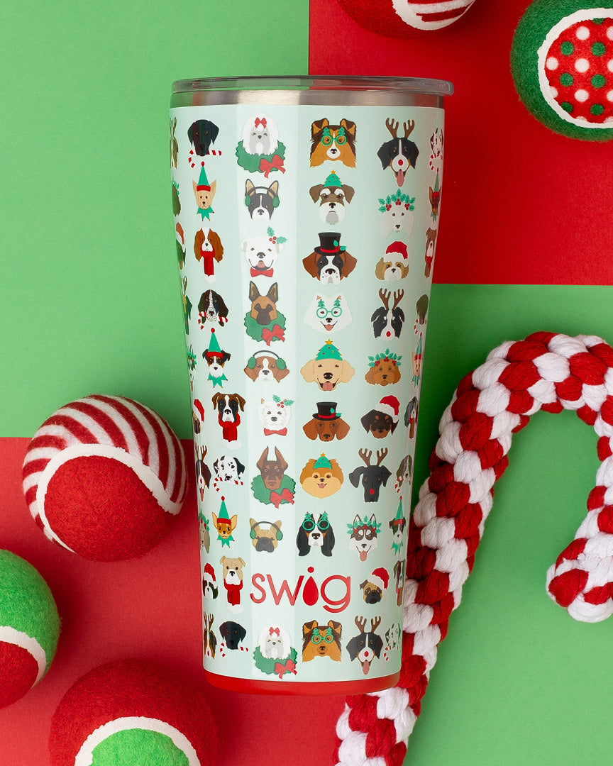 Happy Howlidays 32oz Tumbler set on a red and green background with dog toys