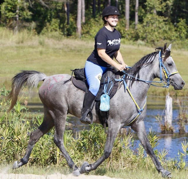 A woman riding on a grey horse on green grass