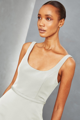 This is an images of a grey fitted women's sleeveless dress incorporating a scoop neck design element.