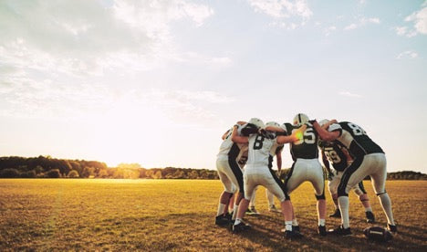 Football players huddled in an open field