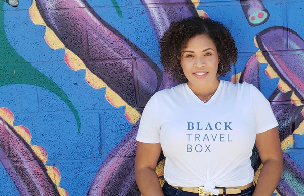 BlackTravelBox | Founder Orion Brown smiling in front of colorful wall in Denver