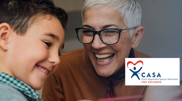 A CASA volunteer laughs while interacting with a young boy.