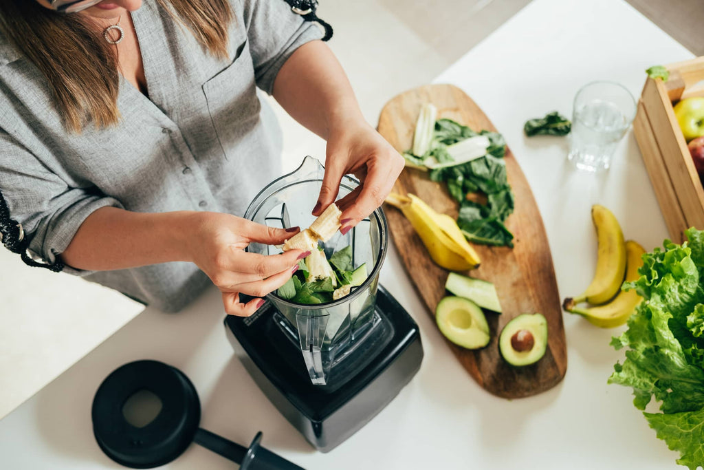 adding pieces of banana to a blender