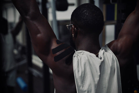 Male wearing Blacktop+ kinesiology tape on his shoulder while he works out.