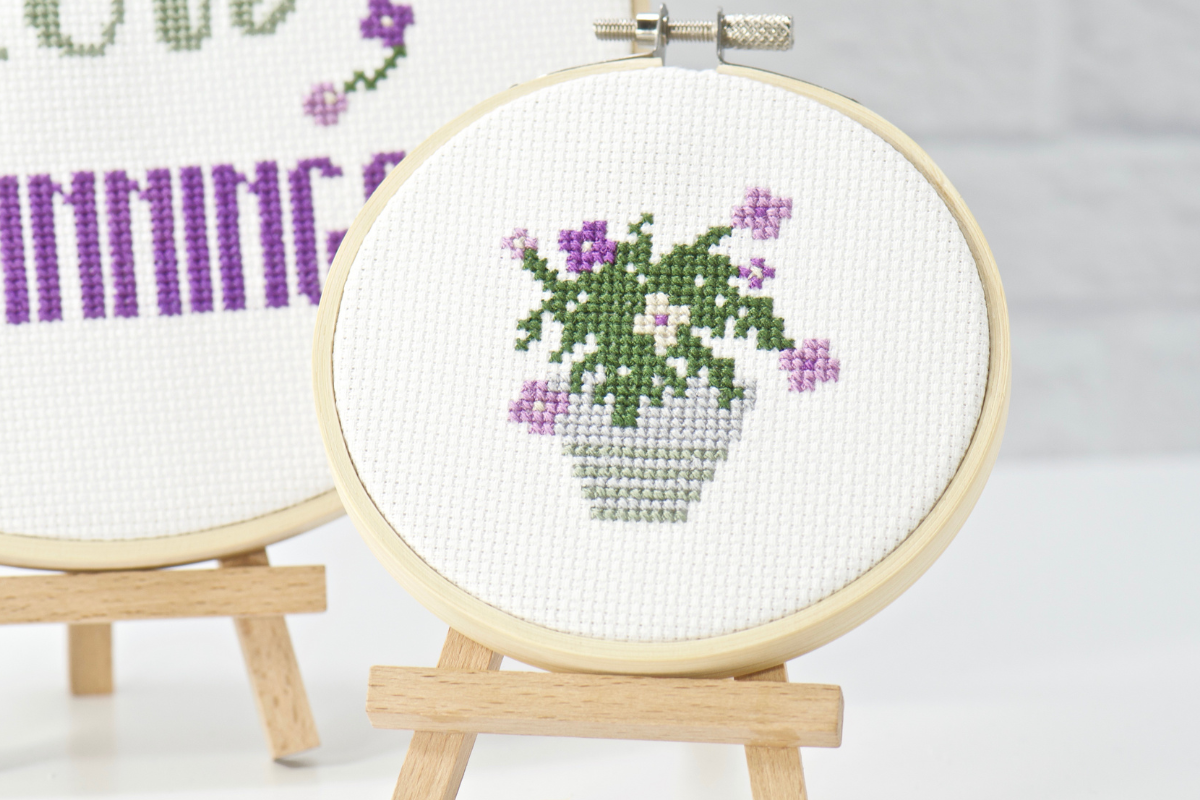 grey cross stitch vase filled with soft purple and beige flowers and greenery in this subscription kit