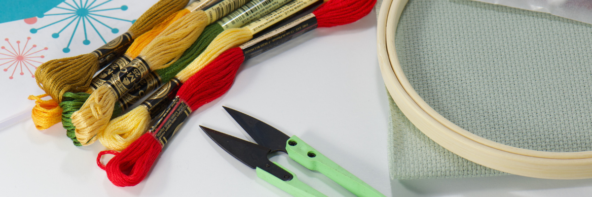 dmc embroidery thread with green embroidery snips cross stitch fabric and wood embroidery hoop supplies