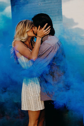 smoke bomb couple with blue smoke surrounding them 