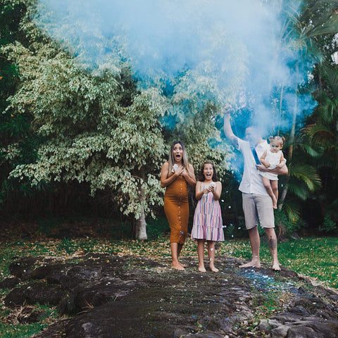 cute family celebrating finding out their babies gender using blue powder gender reveal cannons