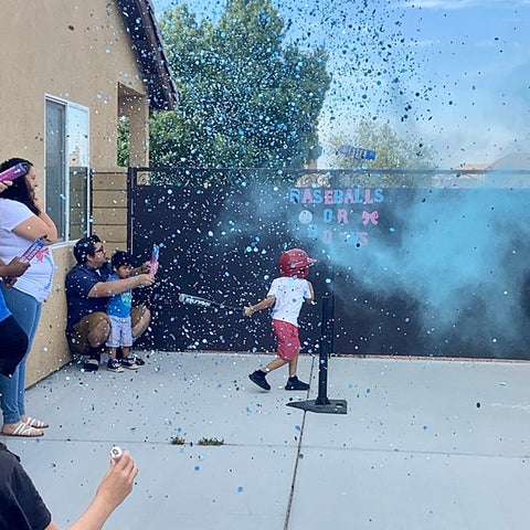 small boy son hitting sibling gender reveal baseball at gender reveal party