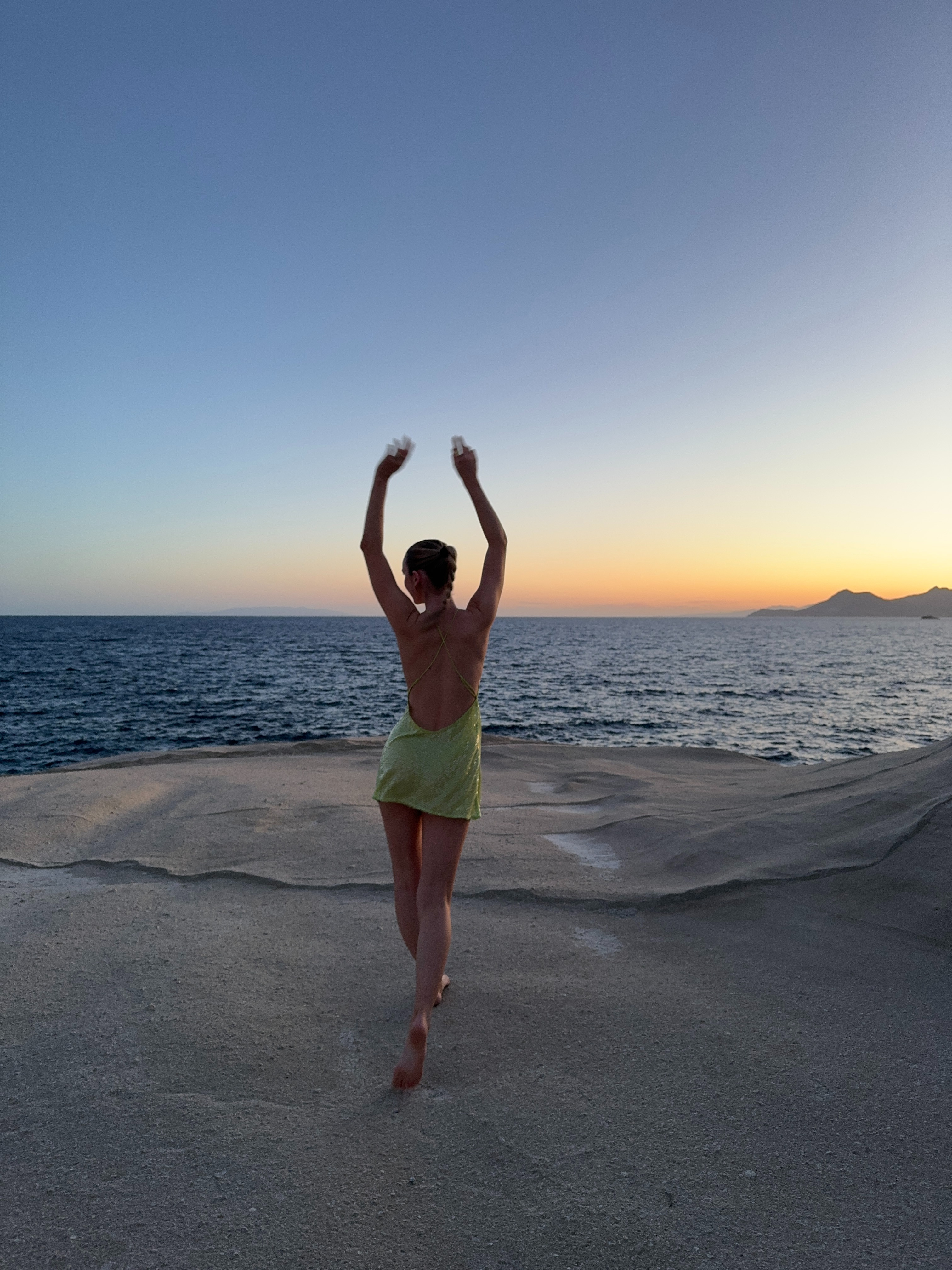 Our social media manager stands elegantly near the beach in a shimmering green resort wear dress, embodying the essence of seaside sophistication.