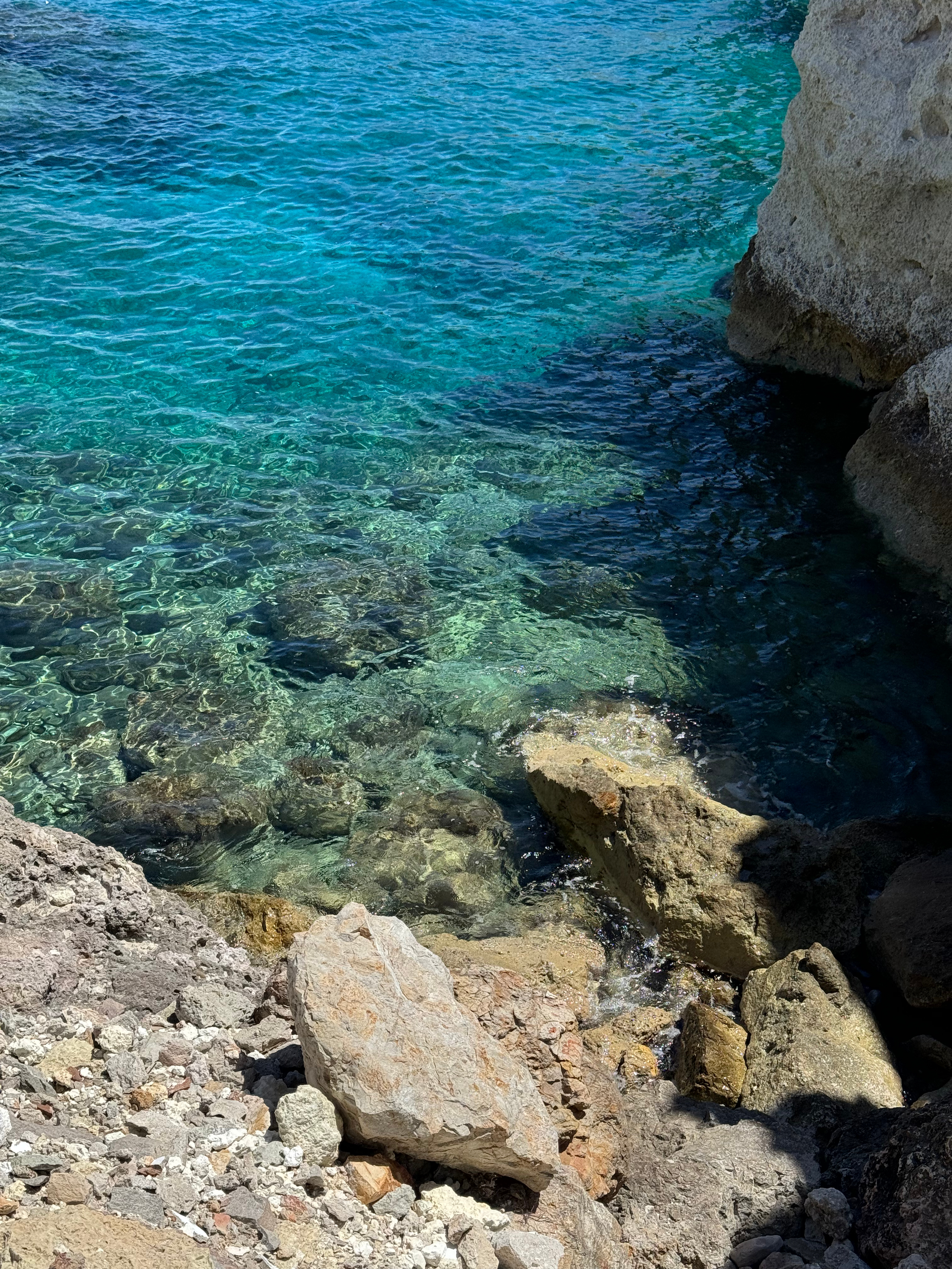 Capturing the mesmerizing close-up view of the tranquil waters in Milos, Greece, with gentle ripples reflecting the serene beauty of the coastline.
