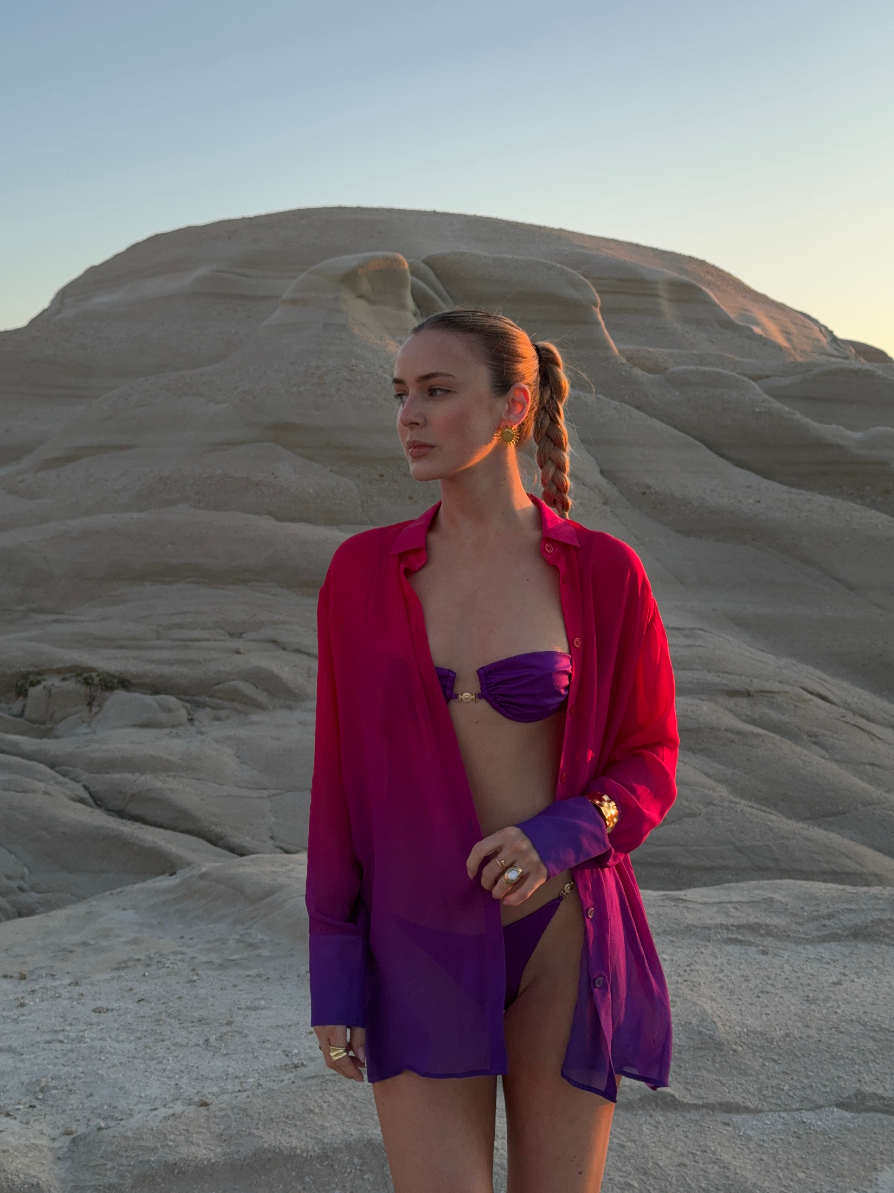 Woman enjoying in the sunlight on a sandy beach, radiating style in a fashionable resort wear.