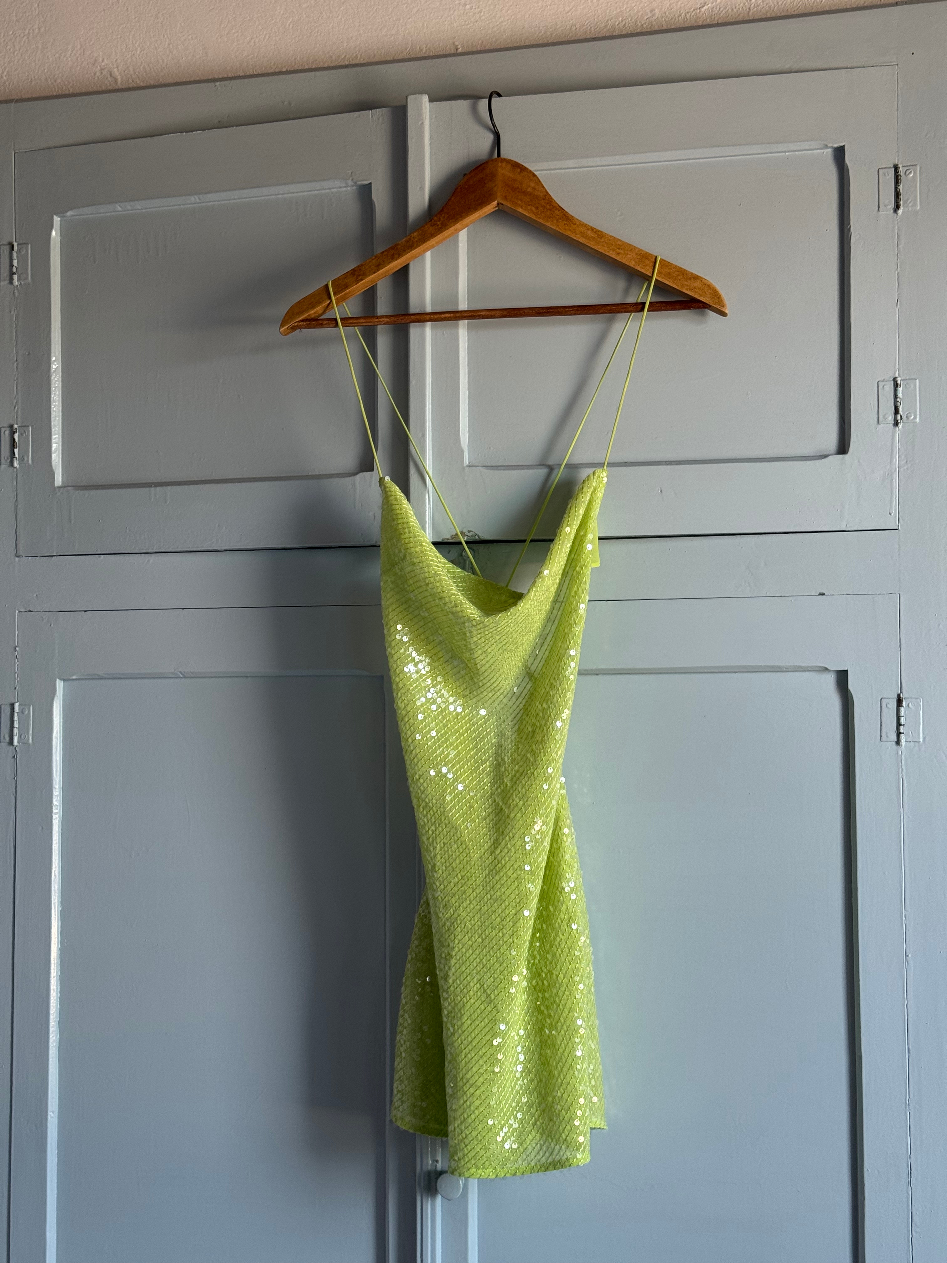 A green shimmery dress hangs gracefully inside our hotel room, adding a touch of elegance to the interior decor