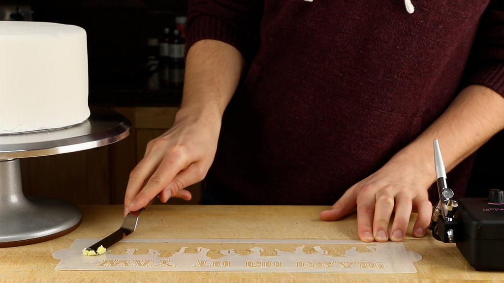 Spread vegetable shortening on the back of your cake stencil