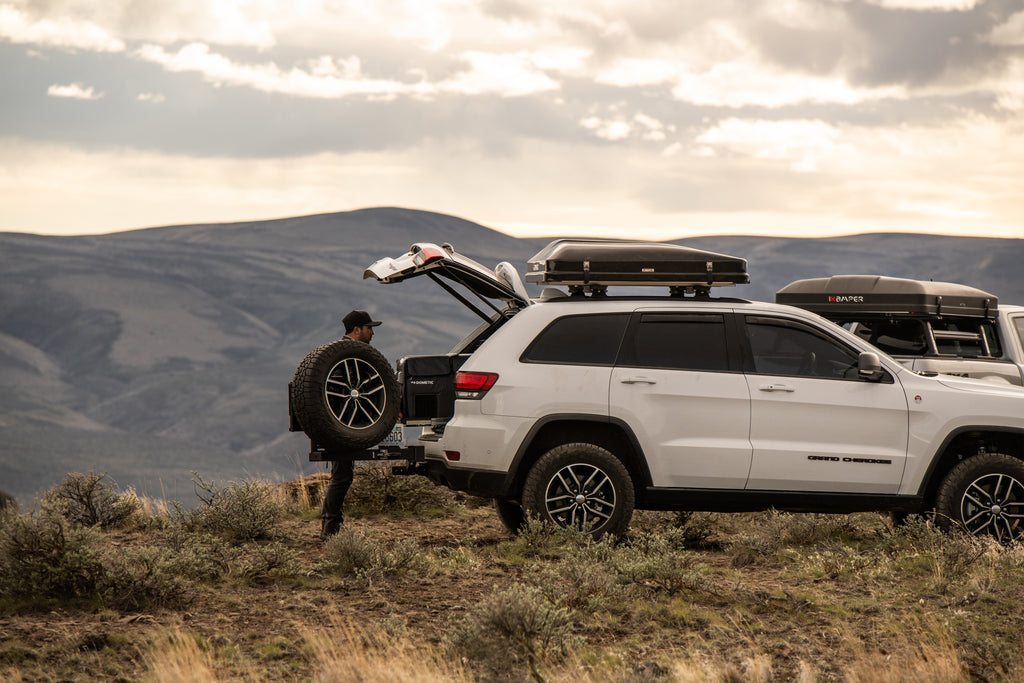 Camper unloading rear cargo from Jeep Grand Cherokee with iKamper Skycamp 2.0 roof top tent