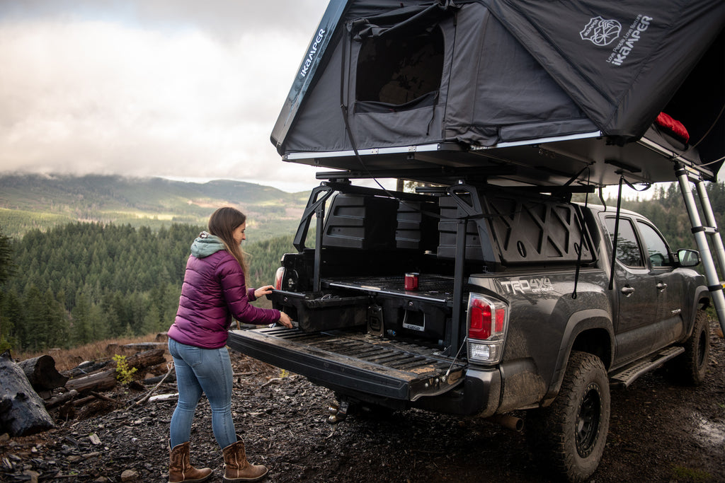 female camper unloading truck bed of Toyota Tacoma with Skycamp 3.0 mounted over bed rack