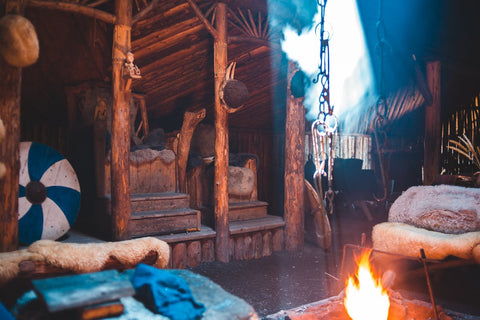 Viking shopping at a Viking scene reenactment such as this one can be a good way to find authentic items. The scene shows a cozy Viking hut, with a burning fire and shields laid against chairs.