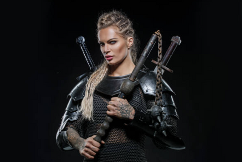 A modern day Viking woman stands holding two ancient weapons