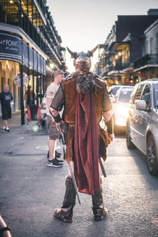 A person in Viking dress standing against the backdrop of a modern street. Bronze Viking jewelry is experiencing a rapid modern resurgence