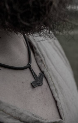 A Thor's hammer norse mythology necklace hangs on the neck of a modern day Viking enthusiast