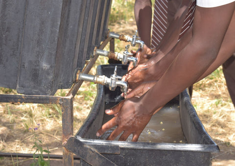 Children in Uganda washing their hands with soap provided by Just a Drop