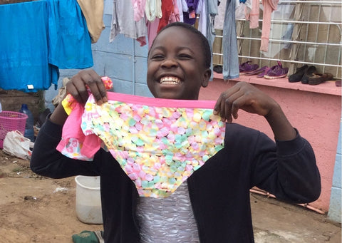 Young Girl Smiles whilst holding a pair of brightly coloured pants