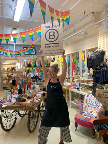Neve holding up the B Corp sign in our Oxford Covered Market shop
