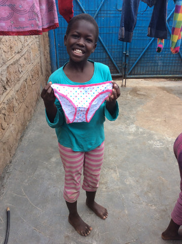 A girl in Kenya holds her new underwear donated by Smalls for All.
