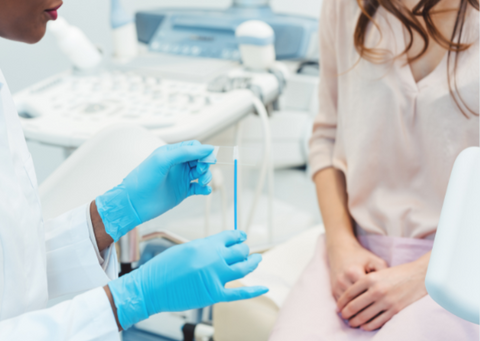 A doctor sits with a woman preparing for a smear test