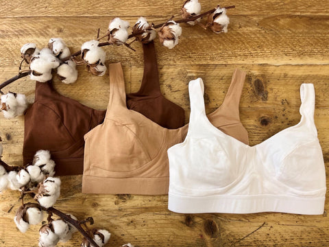 A chestnut, almond & white bra on a wooden background with a cotton plant